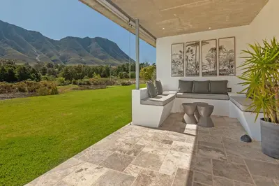a patio with a couch and a field of grass at Villetta in Mosselrivier