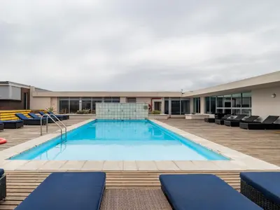 a swimming pool with chairs and a building at Lagoon Shoreline Penthouse in Cape Town