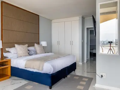 a bedroom with a large bed and a balcony at Lagoon Shoreline Penthouse in Cape Town
