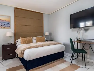 a bedroom with a large bed and a television at Lagoon Shoreline Penthouse in Cape Town