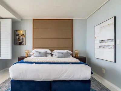 a bedroom with a large bed with a large headboard at Lagoon Shoreline Penthouse in Cape Town