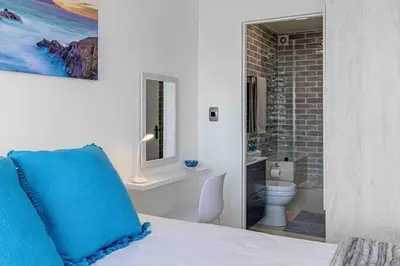 a bedroom with a blue pillow on a bed with a bathroom at Beach Front Sea View Apartment, Table View in Cape Town