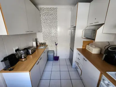 a kitchen with white cabinets and a tile floor at Rondebosch in Cape Town