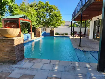 a swimming pool with a gazebo next to a house at Rondebosch in Cape Town