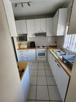 a small kitchen with white cabinets and a sink at Rondebosch in Cape Town