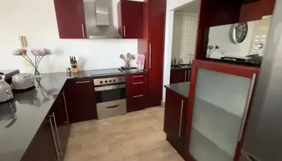 a kitchen with red cabinets and a stove at Ocean View 1004 Luxury Backup Power in Strand