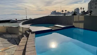 a swimming pool on top of a building next to the water at Ocean View 1004 Luxury Backup Power in Strand