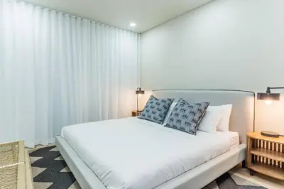 a bedroom with a large white bed with blue pillows at Modern Central 1 BR Apartment in Stellenbosch