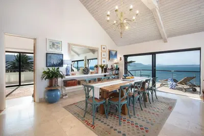 a dining room with a table and chairs and the ocean at Hermanus Luxury Penthouse in Hermanus