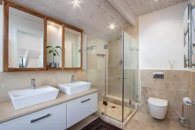 a bathroom with two sinks and a glass shower at Hermanus Luxury Penthouse in Hermanus