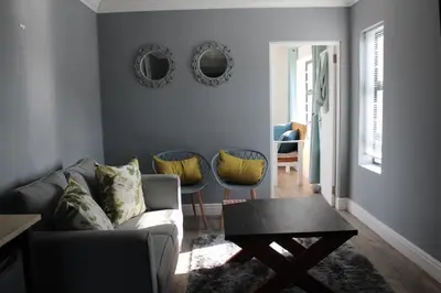 a living room with a couch and a table and mirrors at 17 Suikerbossie in Hermanus