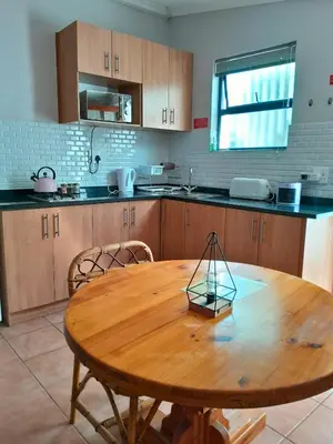 a kitchen with a wooden table with chairs and a table at The High Street Accommodation in Durbanville