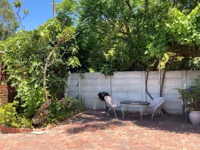 two chairs and a table in front of a fence at The High Street Accommodation in Durbanville
