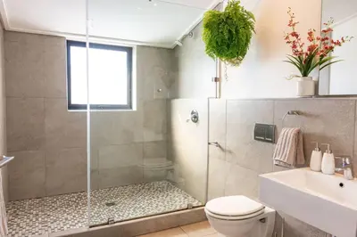a bathroom with a shower and a toilet and a sink at Sea-View Studio - Hermanus Waterfront Apartments in Hermanus