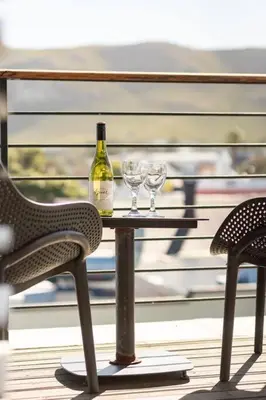 a table with a bottle of wine and two glasses at Sea-View Studio - Hermanus Waterfront Apartments in Hermanus