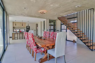 a dining room with a wooden table and chairs at The Dunes in Bettyʼs Bay