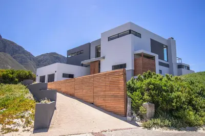 a house on a hill with mountains in the background at The Dunes in Bettyʼs Bay