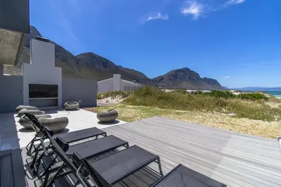 a deck with chairs and a view of the ocean at The Dunes in Bettyʼs Bay