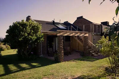 a brick house with a patio and a tree at Cozy House & Studio with Sea and Mountain Views in Bettyʼs Bay