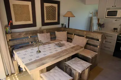 a kitchen with a wooden table and chairs and a table and chairsearcher at Cozy House & Studio with Sea and Mountain Views in Bettyʼs Bay