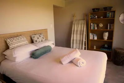 a bedroom with a bed with two rolled towels on it at Cozy House & Studio with Sea and Mountain Views in Bettyʼs Bay