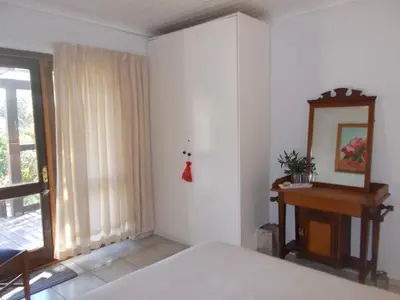 a bedroom with a bed and a table and a window at Erf 473 Fisherhaven in Fisherhaven