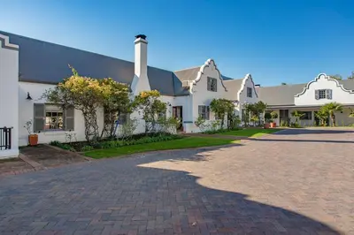 a large white house with a brick driveway at Franschhoek Manor in Franschhoek
