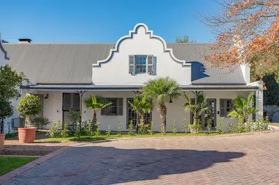 a white house with palm trees in front of it at Franschhoek Manor in Franschhoek