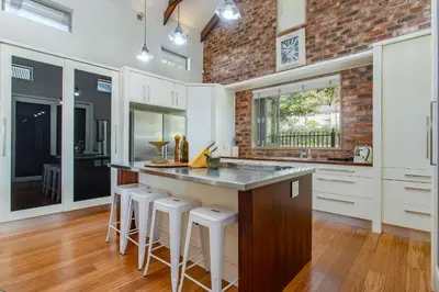 a kitchen with white cabinets and a bar with stools at Swallows Summer Home in Paarl