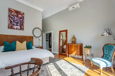 a bedroom with a bed and a chair and a mirror at Swallows Summer Home in Paarl