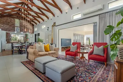 a living room with a couch and two red chairs at Swallows Summer Home in Paarl