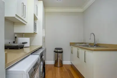 a kitchen with white cabinets and a sink at Swallows Summer Home in Paarl