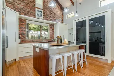 a kitchen with a large counter with stools in it at Swallows Summer Home in Paarl