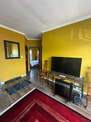 a yellow living room with a large flat screen tv at Affordable Luxury in Cape Town
