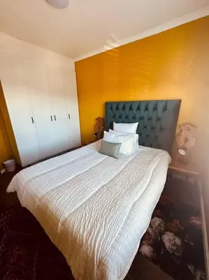a bedroom with a bed with a blue headboard at Affordable Luxury in Cape Town