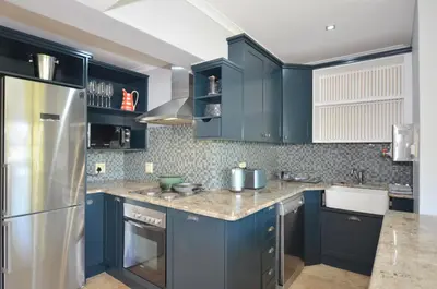 a kitchen with blue cabinets and a stainless steel refrigerator at Church View Lux Apartment in Stellenbosch