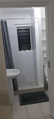 a bathroom with a shower with a sink and a window at Convenient Comfort in Cape Town