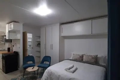 a bedroom with a bed and two blue chairs at Convenient Comfort in Cape Town