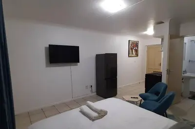 a bedroom with a bed and a tv and a chair at Convenient Comfort in Cape Town