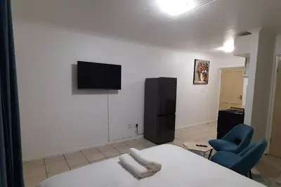 a bedroom with a bed and a chair and a television at Convenient Comfort in Cape Town
