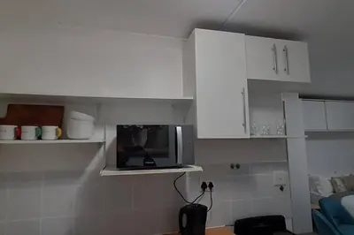a kitchen with white cabinets and a microwave at Convenient Comfort in Cape Town