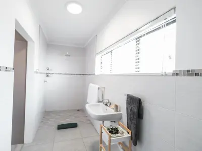 a white bathroom with a sink and a shower at Hermanus Reefs in Hermanus