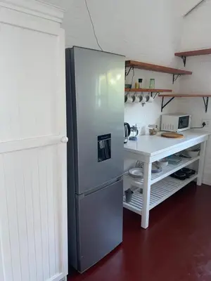 a refrigerator in a kitchen with a desk at Two Palms Cottage in Hermanus