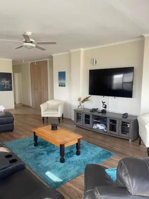 a living room with a tv and a coffee table at Sea View Serenity on Strand in Cape Town