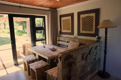 a dining room with a wooden table and chairs at Fynbos Cottage with Sea View - Self-catering in Bettyʼs Bay