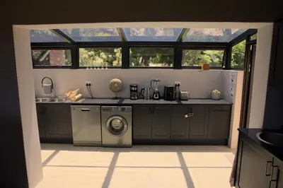 a kitchen with a sink and a washing machine at Cozy House with Sea and Mountain Views in Bettyʼs Bay