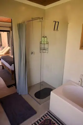 a bathroom with a shower with a tub and a sink at Cozy House with Sea and Mountain Views in Bettyʼs Bay