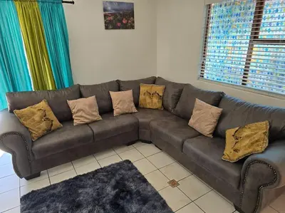 a brown couch with pillows in a living room at Super Cosy Cottage in quiet area VanzylsRus in Cape Town