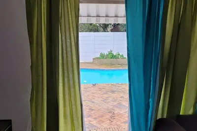 a view of a swimming pool through a window at Super Cosy Cottage in quiet area VanzylsRus in Cape Town