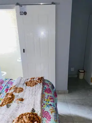 a bedroom with a bed and a white wall at 22clyde street bostin in Cape Town